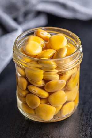 Lupini beans in brine. Pickled lupine in jar on the black table.の写真素材