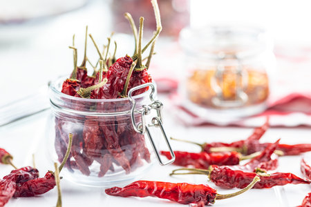Red chili peppers in jar on the white table.の写真素材