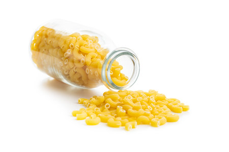 Raw macaroni pasta in glass bottle. Uncooked rigatoni isolated on the white background.の写真素材
