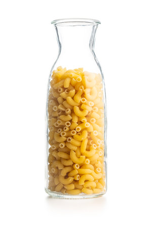 Raw macaroni pasta in glass bottle. Uncooked rigatoni isolated on the white background.の写真素材