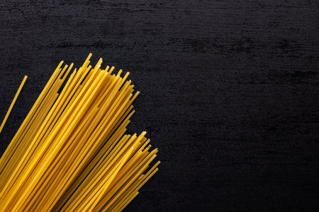 Spaghetti pasta. Uncooked italian pasta on a black table. Top view.の写真素材