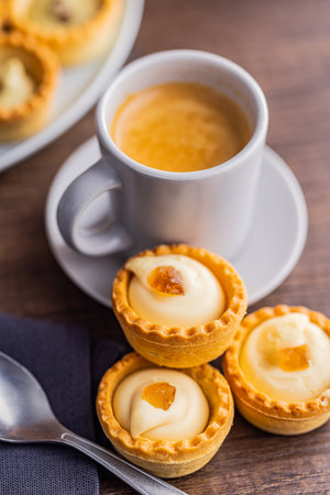 Sweet tartlets. Tasty mini tarts. Mini pie with cream and coffee cup on the kitchen table.の写真素材