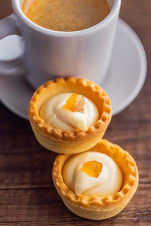 Sweet tartlets. Tasty mini tarts. Mini pie with cream and coffee cup on the kitchen table.の写真素材