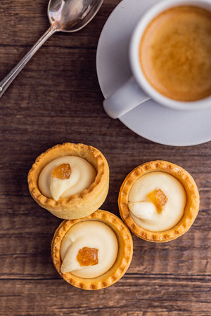 Sweet tartlets. Tasty mini tarts. Mini pie with cream and coffee cup on the kitchen table. Top view.の写真素材