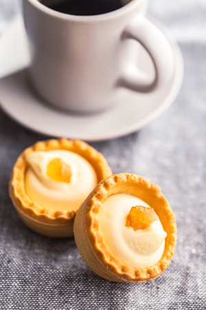 Sweet tartlets. Tasty mini tarts. Mini pie with cream and coffee cup on the kitchen table.の写真素材