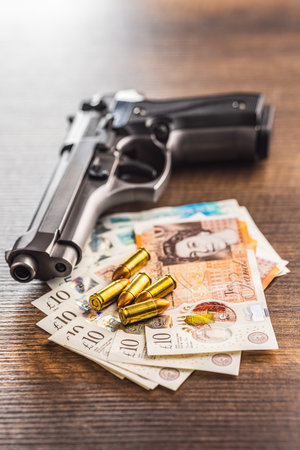 Handgun, bullets and British pound sterling on the wooden table.の写真素材
