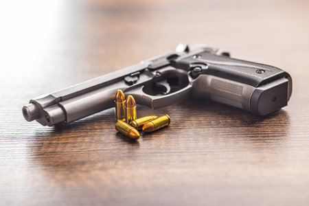 Handgun and bullets on the wooden table.の写真素材