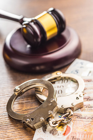 Judge gavel, handcuffs and British pound sterling on the wooden table.の写真素材