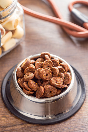 Dry animal food. Dog or cat kibble isolated in bowl on the wooden table.の写真素材