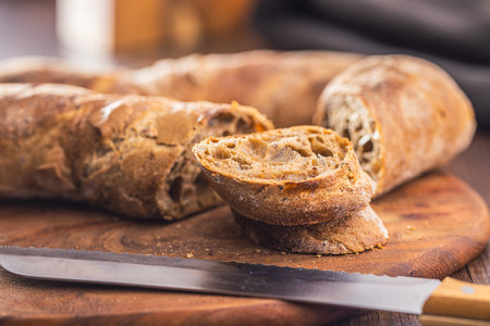 Sliced wholegrain rustic baguette on the wooden table.の写真素材