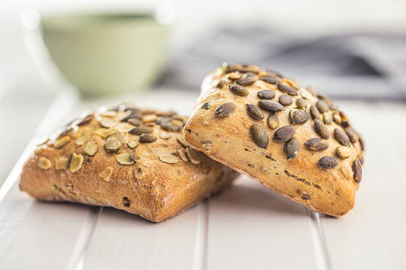 Whole grain bun with pumpkin seeds on the white table.の写真素材