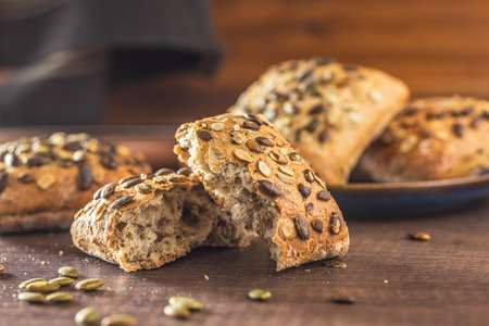 Whole grain bun with pumpkin seeds on the wooden table.の写真素材
