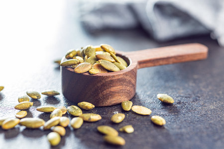 Peeled pumpkin seeds in wooden spoon on the kitchen table.の写真素材
