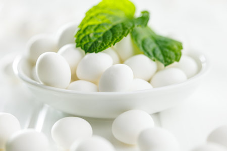 Mint candies in bowl. Menthol candies and mint leaves on the white table.の写真素材