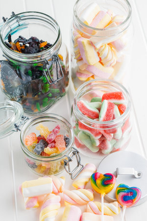 Sweet colorful marshmallows and jelly candies on the white kitchen table.の写真素材