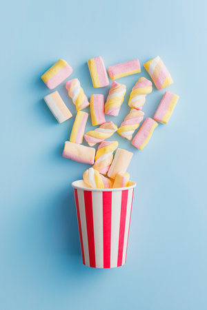 Sweet colorful marshmallows in a cup on the blue background. Top view.の写真素材