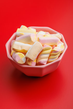 Sweet colorful marshmallows in a bowl on the red table.の写真素材