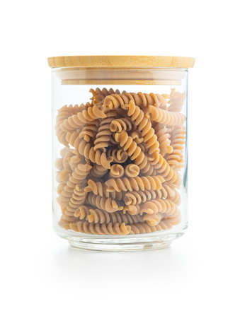 Raw whole grain fusilli pasta. Uncooked pasta in a jar isolated on the white background.の写真素材