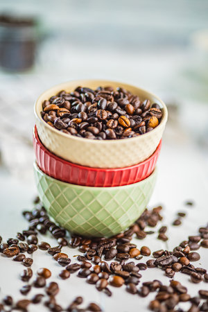 Roasted coffee beans in a bowl on the white kitchen table.の写真素材