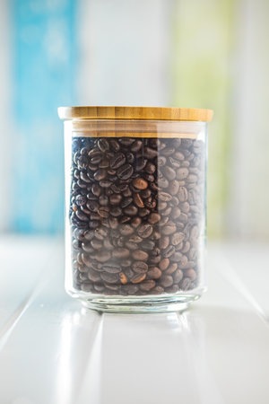 Roasted coffee beans in a jar on the white kitchen table.の写真素材