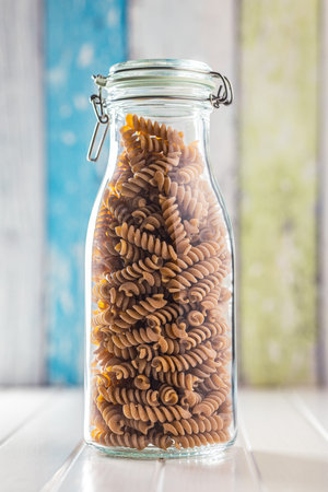 Raw whole grain fusilli pasta. Uncooked pasta in the jar.の写真素材