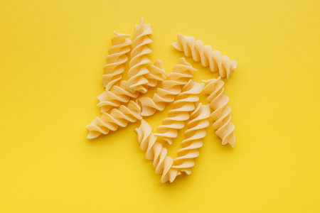 Uncooked fusilli pasta. Uncooked italian pasta on the yellow background.の写真素材