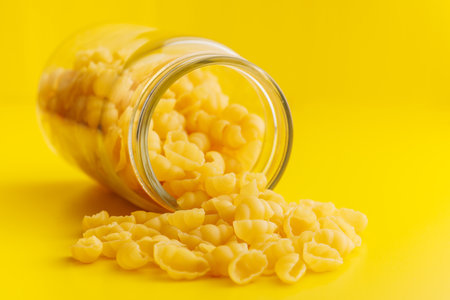 Uncooked gnocchi pasta. Raw italian pasta in a jar on the yellow background.の写真素材