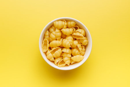 Uncooked gnocchi pasta. Raw italian pasta in a bowl on the yellow background.の写真素材
