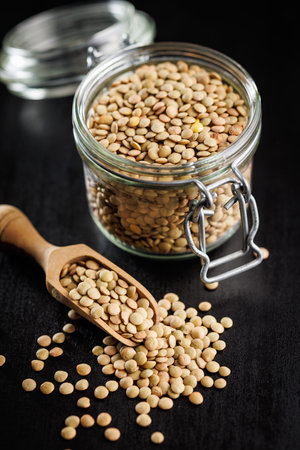Uncooked lentil legumes in jar on the black table.の写真素材