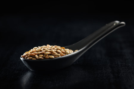 Uncooked lentil legumes in ceramic spoon on the black table.の写真素材