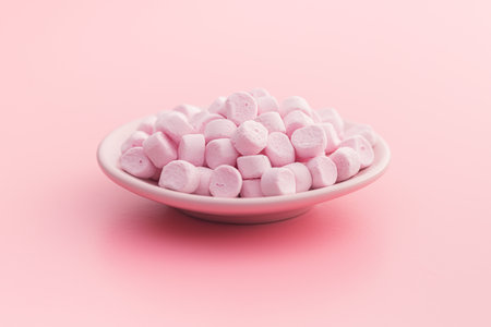 Mini sweet marshmallows candy on plate on the pink background.の写真素材