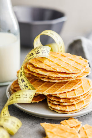 Round waffle biscuits and measuring tape on the kitchen table.の写真素材