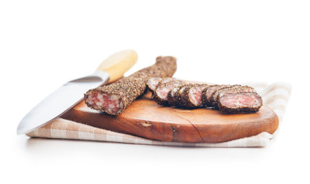 Smoked dried sausage. Sliced sausage on cutting board isolated on the white background.の写真素材