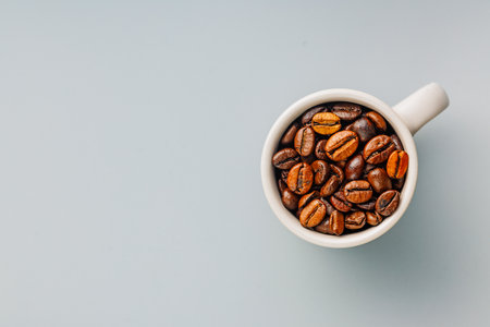 Roasted coffee beans in a coffee cup on the gray background. Top view.の写真素材