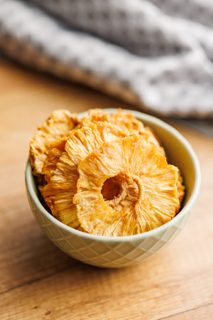 Dried pineapple rings in a bowl on the wooden table.の写真素材