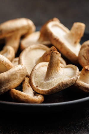 The fresh shiitake mushrooms on a plate on the black table.の写真素材