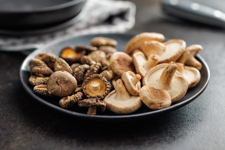 The fresh and dried shiitake mushrooms on a plate on the black table.の写真素材