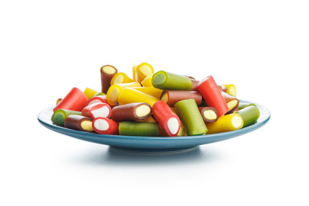 Sweet colorful chewy candy sticks on a plate isolated on the white background.の写真素材
