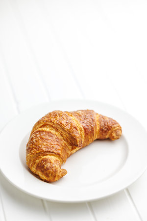 Baked tasty croissant on plate on the white table.の写真素材