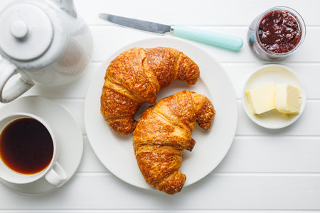 Two baked tasty croissants on a plate on the white table. Top view.の写真素材