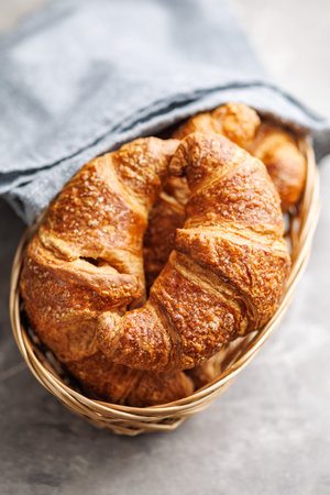Baked tasty croissants in basket on the kitchen table.の写真素材