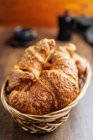 Baked tasty croissants in basket on the wooden table.の写真素材