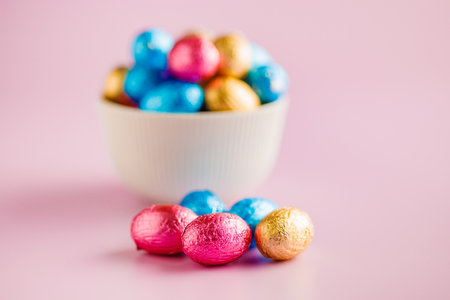 Easter chocolate eggs wrapped in aluminum foil on the pink background.