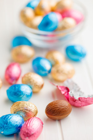 Easter chocolate eggs wrapped in aluminum foil on the white table.の写真素材