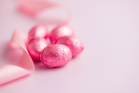 Easter chocolate eggs wrapped in aluminum foil on the pink background.の写真素材