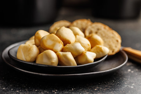 Smoked mini scamorza cheese. Traditional italian cheese on plate on the black table.
