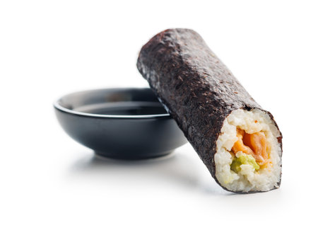 A sushi roll neatly sliced and displayed with a side of savory soy sauce. The sushi features fresh fish, rice, and vegetables rolled in seaweed, while the soy sauce complements the flavors.の写真素材
