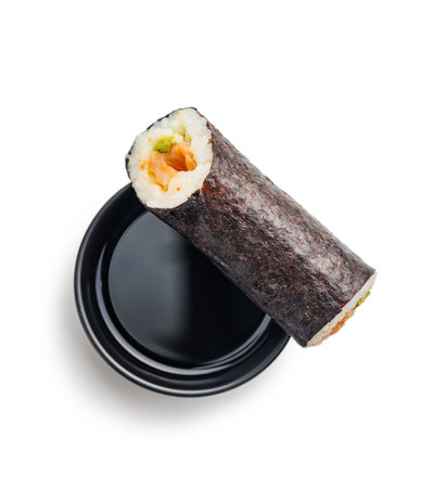 A sushi roll neatly sliced and displayed with a side of savory soy sauce. The sushi features fresh fish, rice, and vegetables rolled in seaweed, while the soy sauce complements the flavors.の写真素材