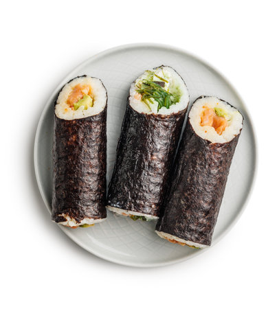 A white plate is placed on a white table, with an assortment of sushi neatly arranged on top. The sushi pieces glisten under the light, showcasing their vibrant colors and textures.の写真素材