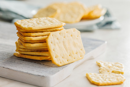 Golden Baked Crackers on a cutting board on a White kitchen table.